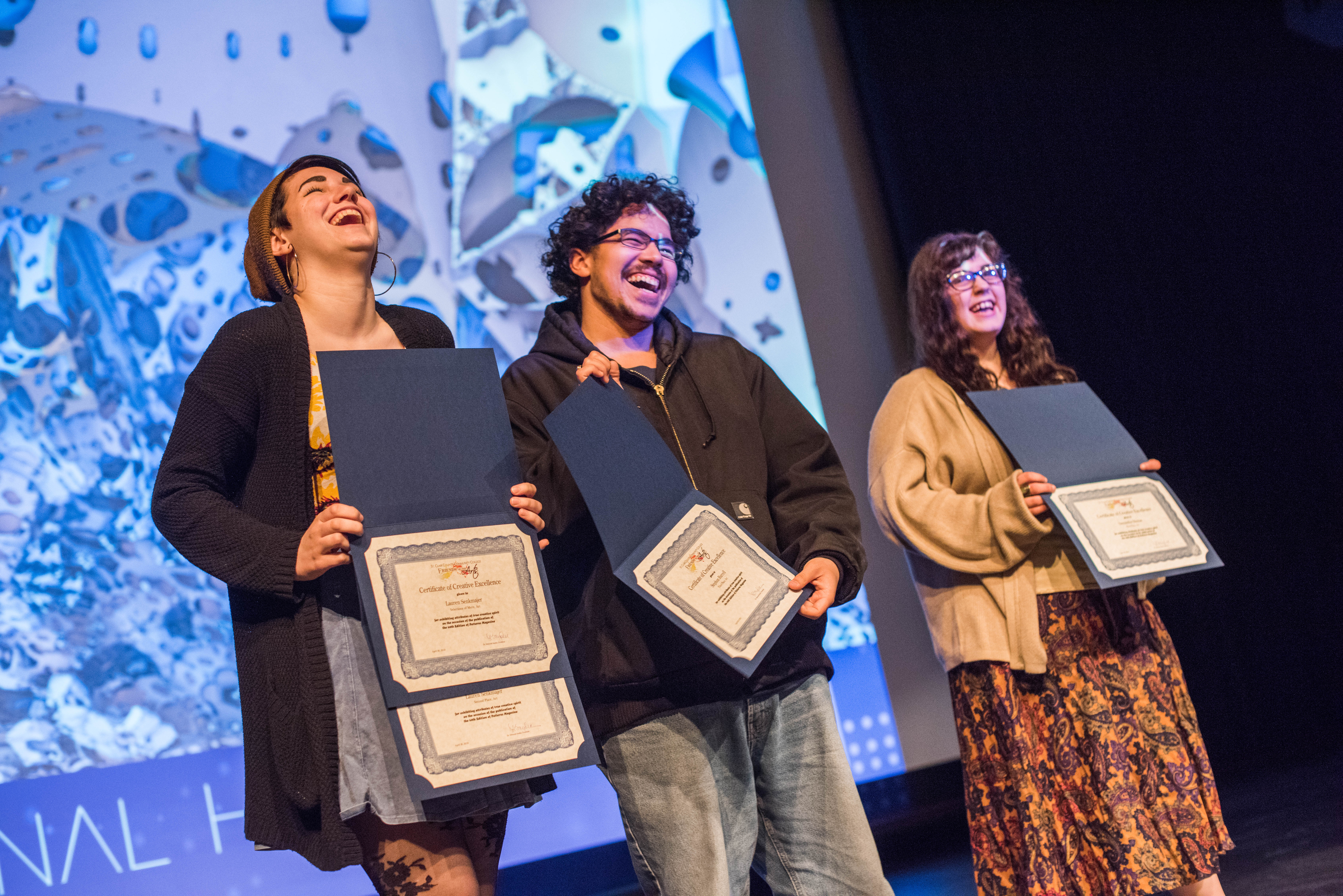 Three Students laugh as they hold their awards