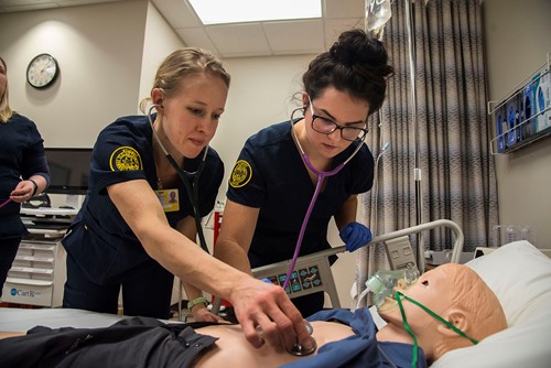 Two nursing students work on a manikin.