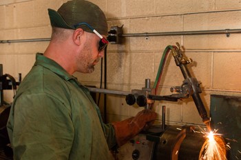 Welding student working with a tool.