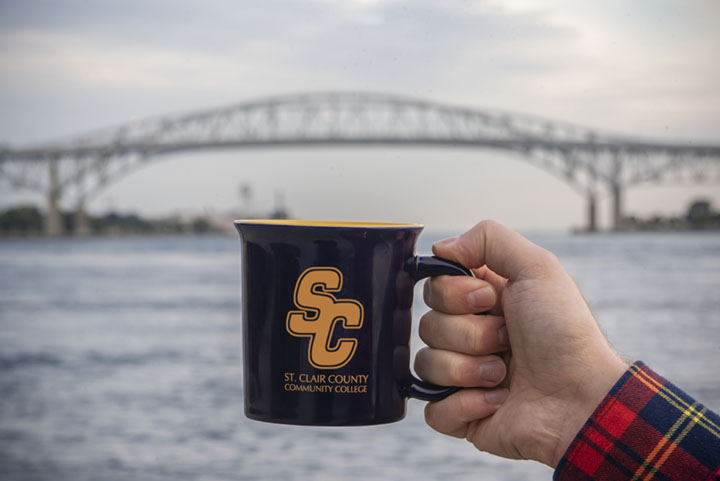 Hand holding SC4 coffee mug in front of Blue Water Bridge.