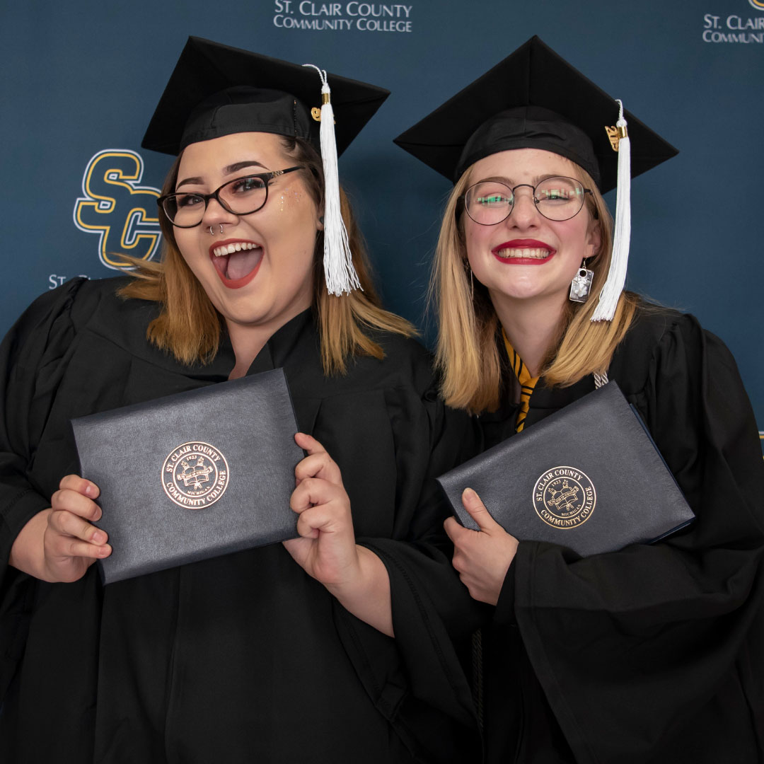 Grads smiling and holding degree